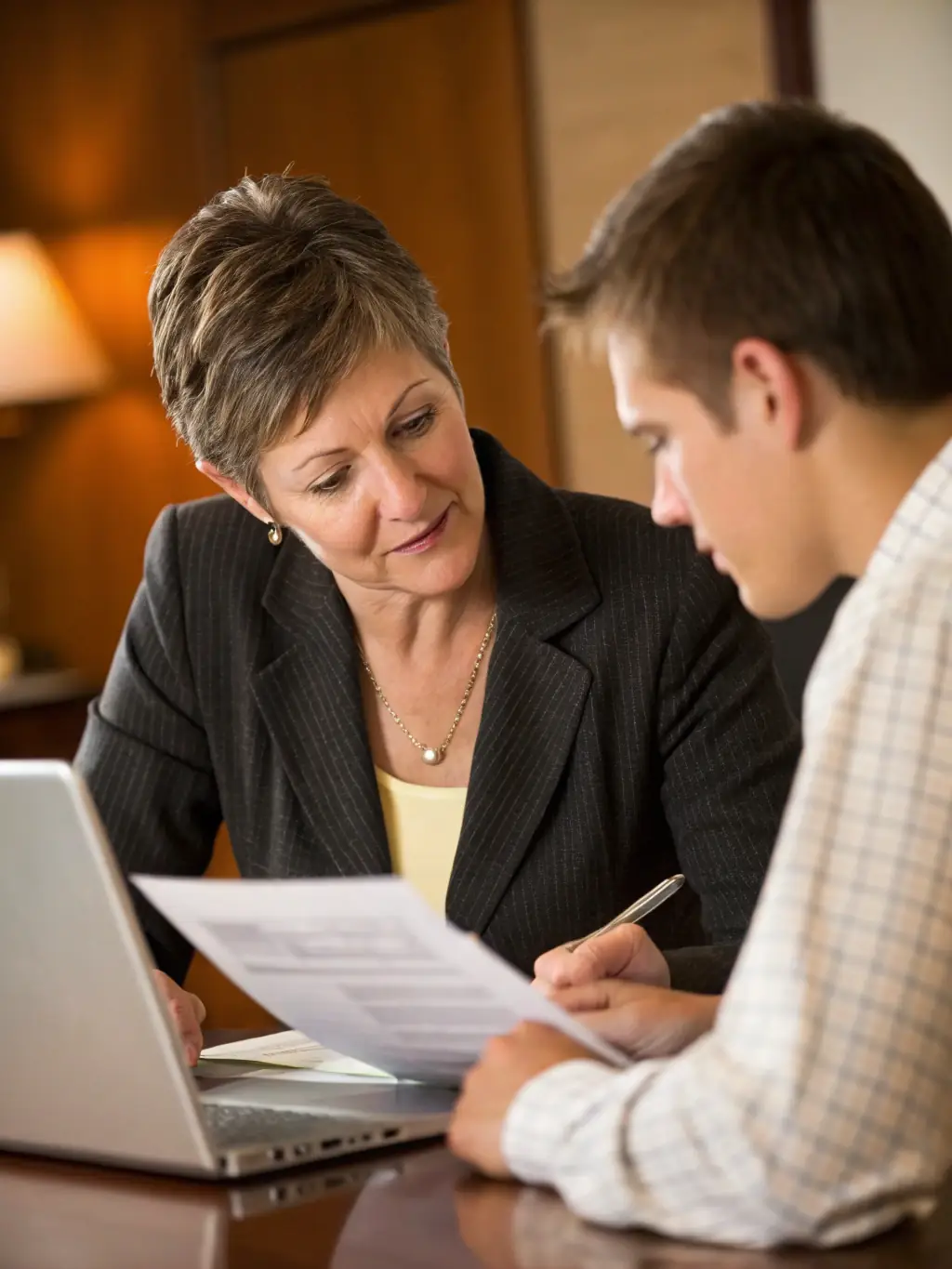 A warm and professional advisor smiling while shaking hands with a satisfied senior client in a sunny office, symbolizing trust and personalized service.